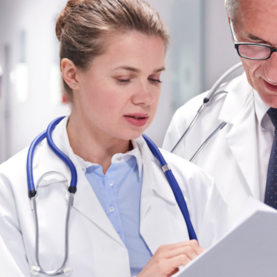 Doctors in lab coats consulting over chart in corridor