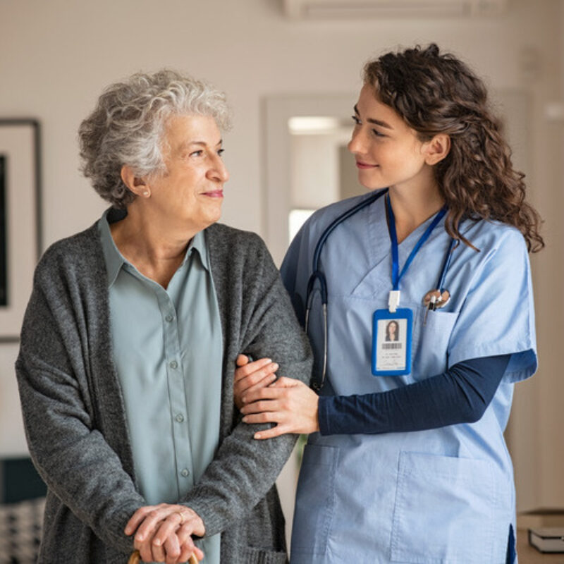 Nurse and elderly patient standing in hallway together